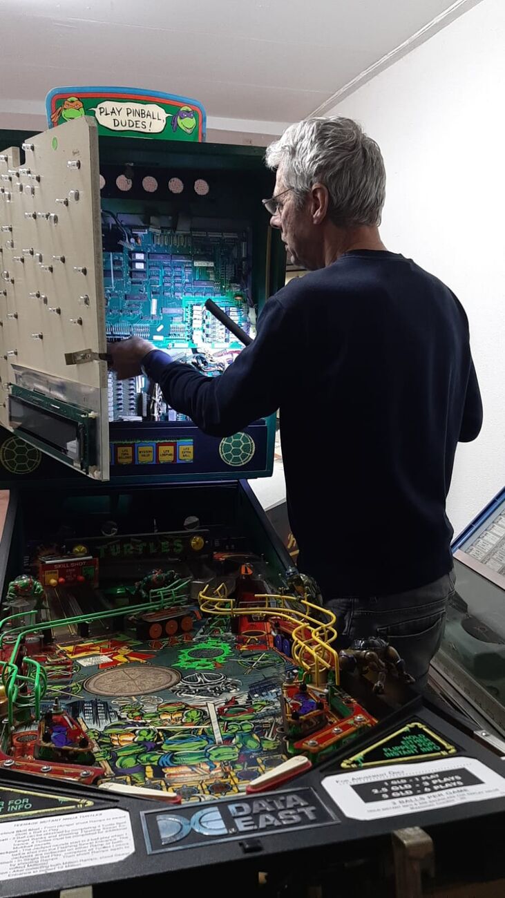 Bert Hollander aan het werk aan een flipperkast in de werkplaats